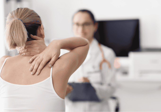 Patient with hands on back of neck/shoulder consulting with a doctor.