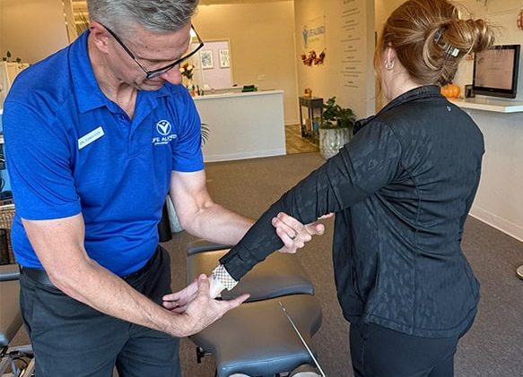 Dr. Cox performing a chiropractic arm adjustment on a patient inside a modern wellness clinic.