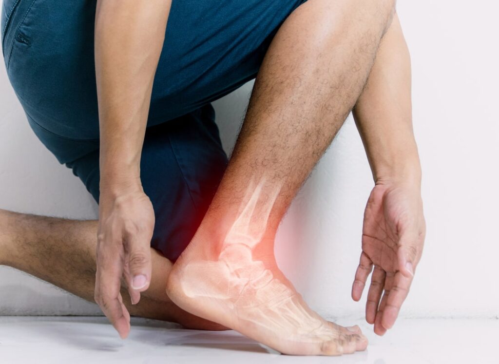 Person holding ankle in pain with a highlighted skeletal overlay showing inflammation or injury.