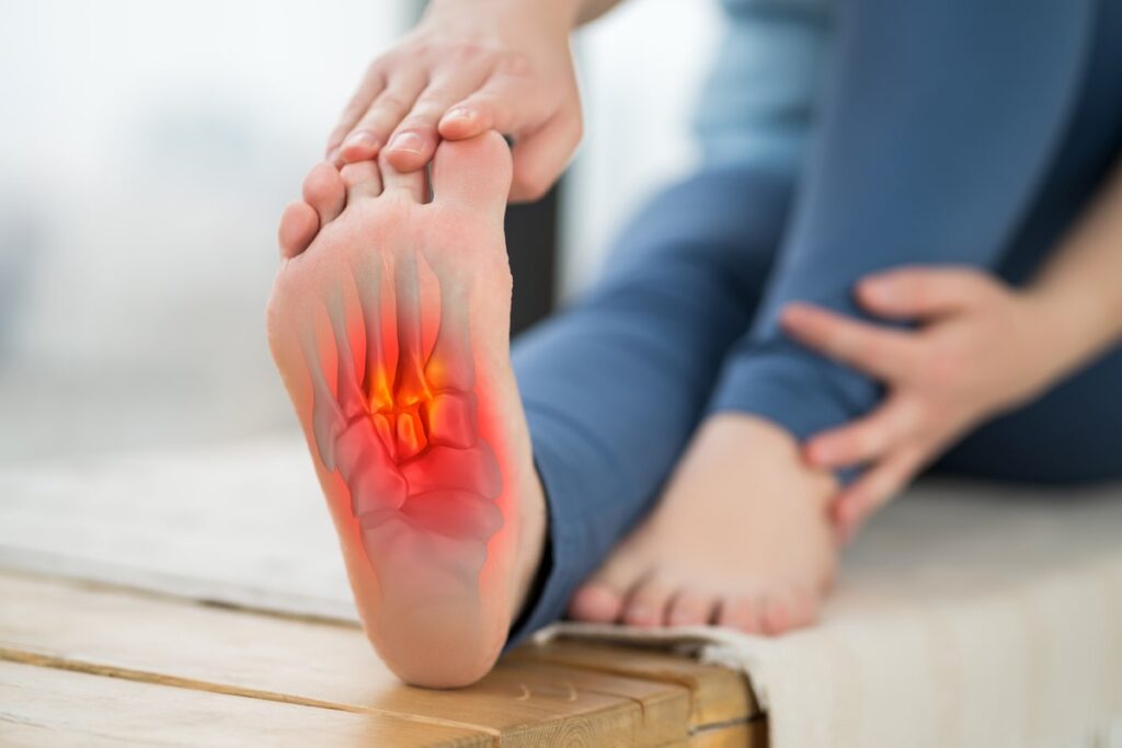 Close-up of a person holding their inflamed foot with highlighted pain in the arch, indicating plantar fasciitis or foot strain.