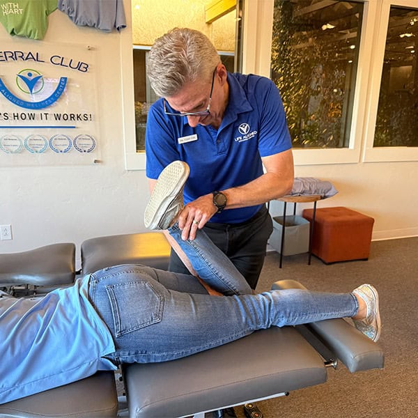Chiropractor performing a knee stretch on a patient during therapeutic treatment at Life Aligned Wellness Center.