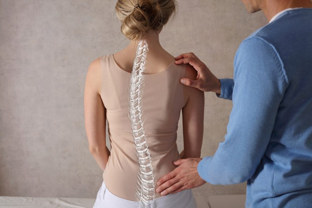 Chiropractor examining a woman’s spine, overlaid with a digital illustration of the spine.