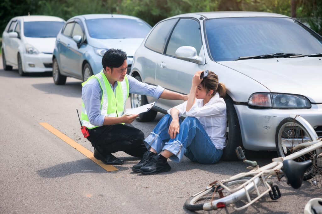 Traffic official assisting injured woman after a bicycle and car accident