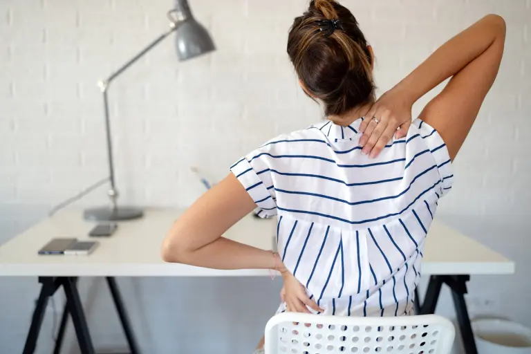 Woman stretching her back due to chronic lower back pain.
