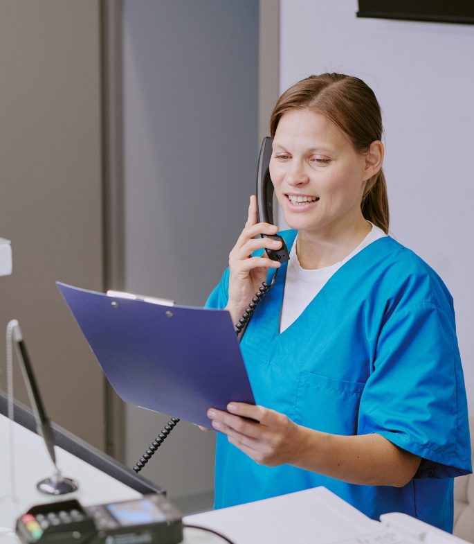 Nurse speaking on the phone while looking at a chart.