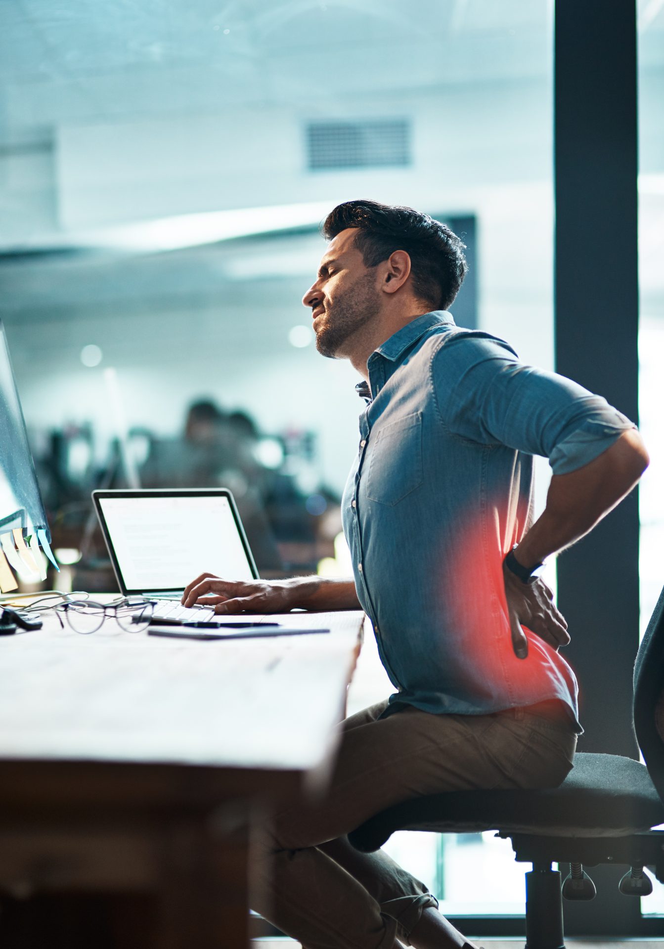 man sitting at desk showing low back pain