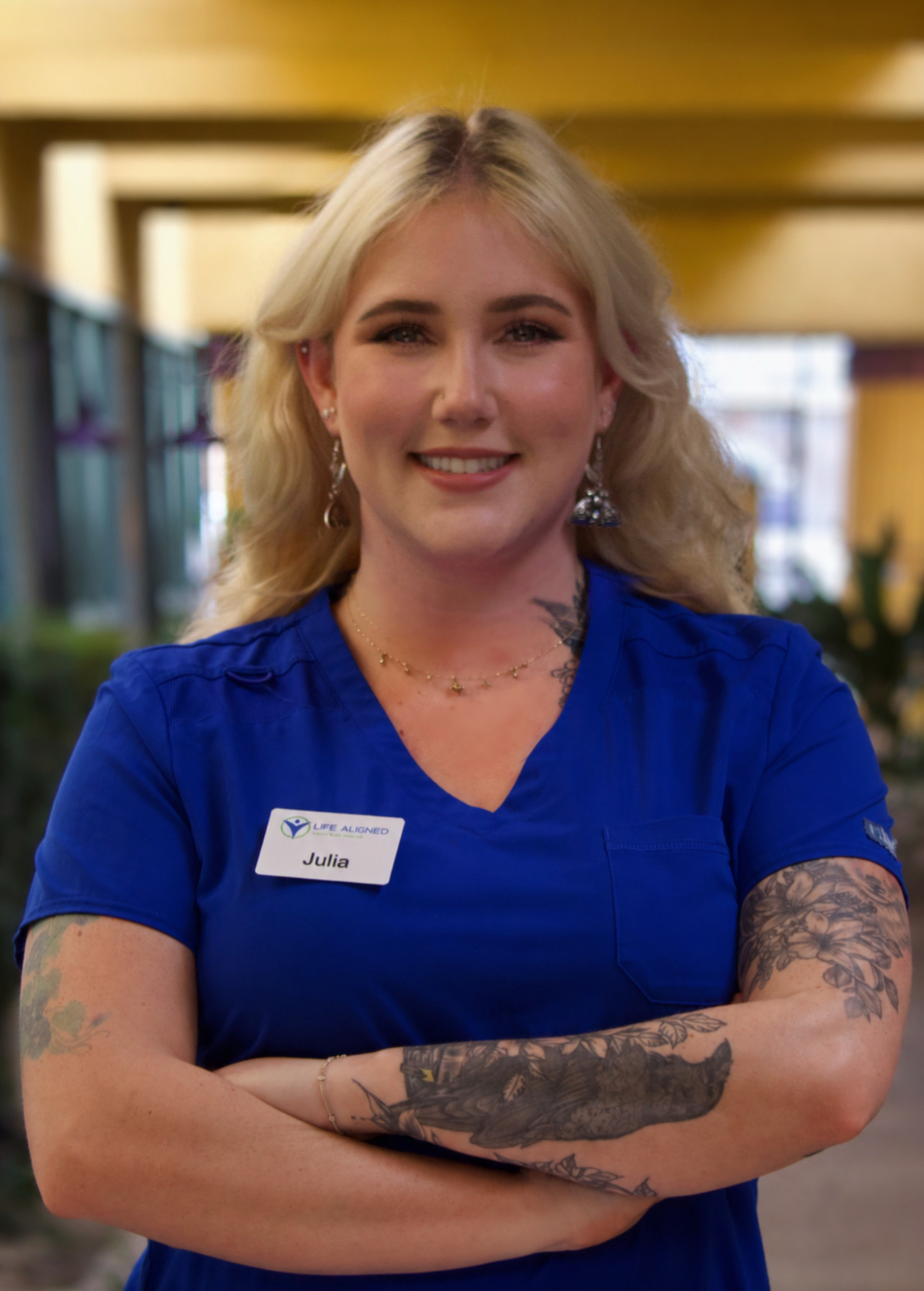Julia, Rehab Chiropractic Assistant, smiling warmly in blue scrubs at the clinic.