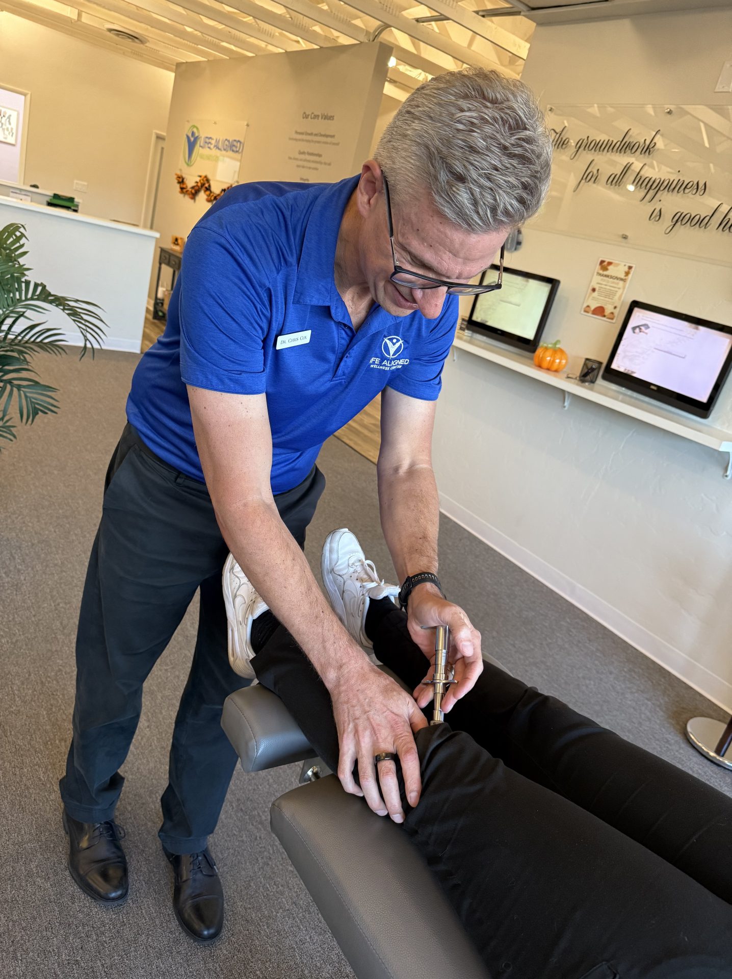 Chiropractor applying a handheld adjusting instrument to a patient’s knee at Life Aligned Wellness Center.